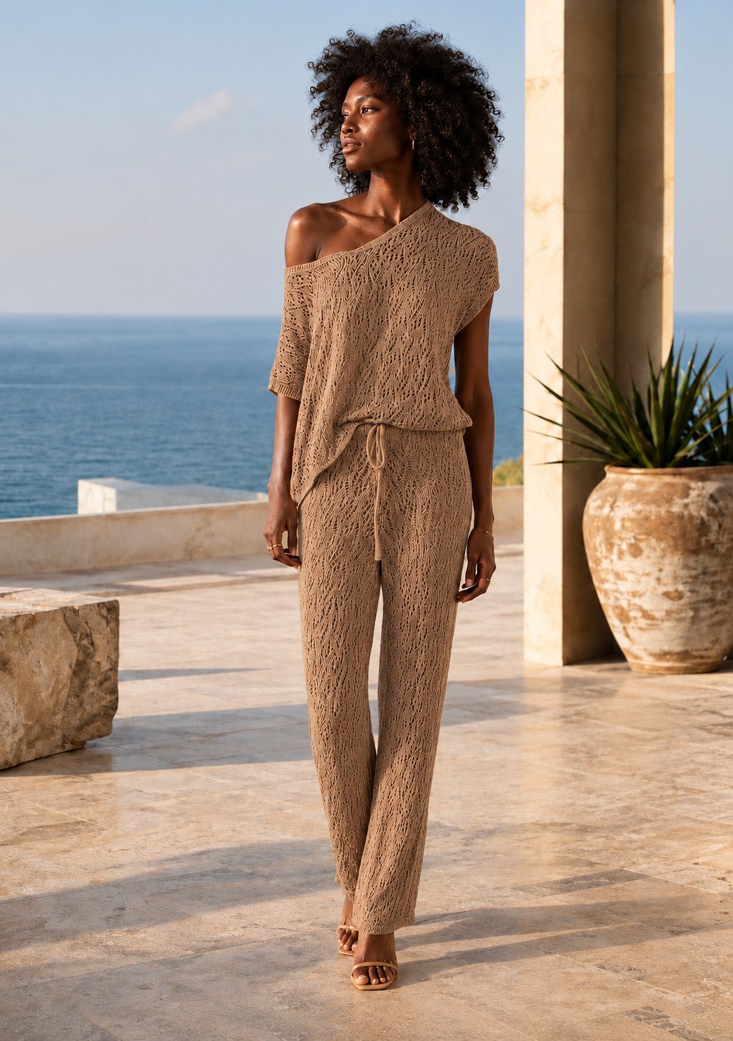 Conjunto tricô vazado bege, blusa com um ombro à mostra e calça, terraço à beira-mar